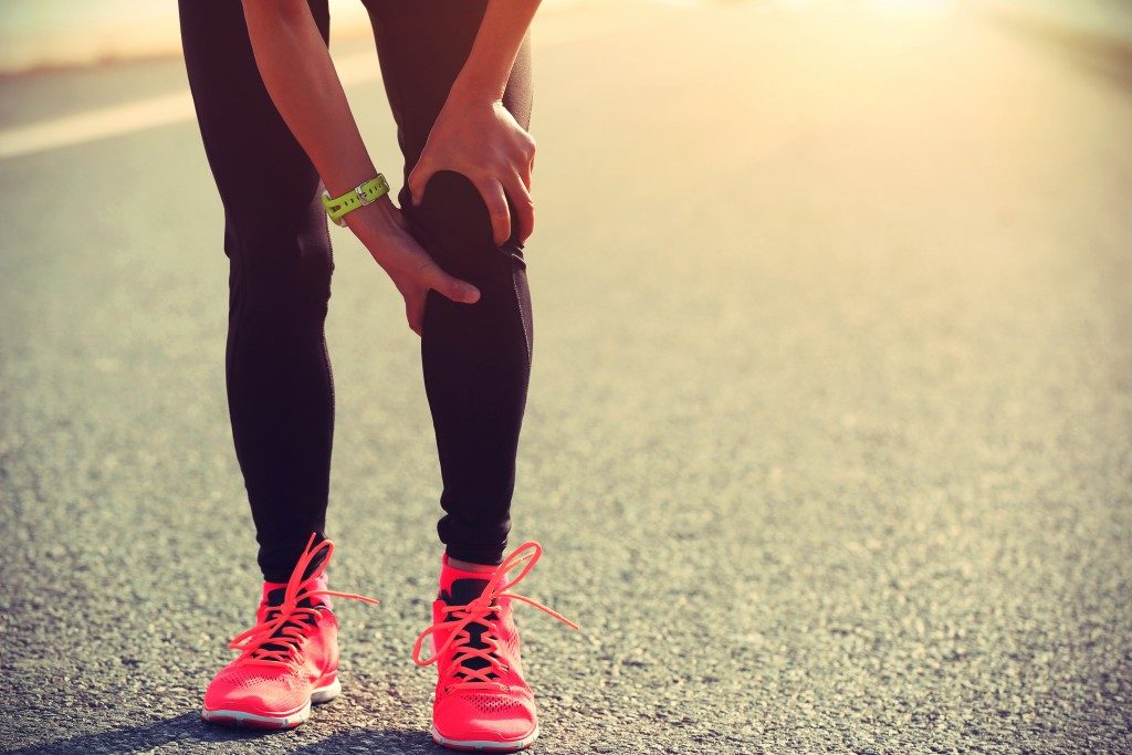 running holding knee in pain