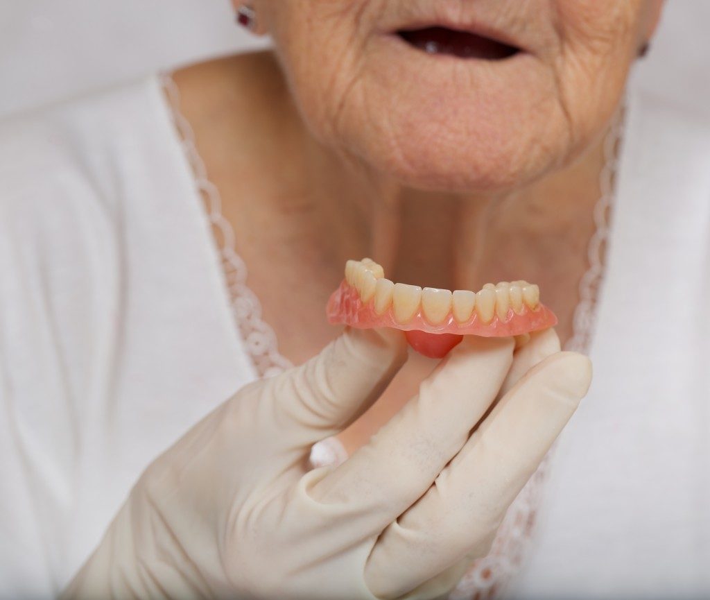 elderly woman holding dentures