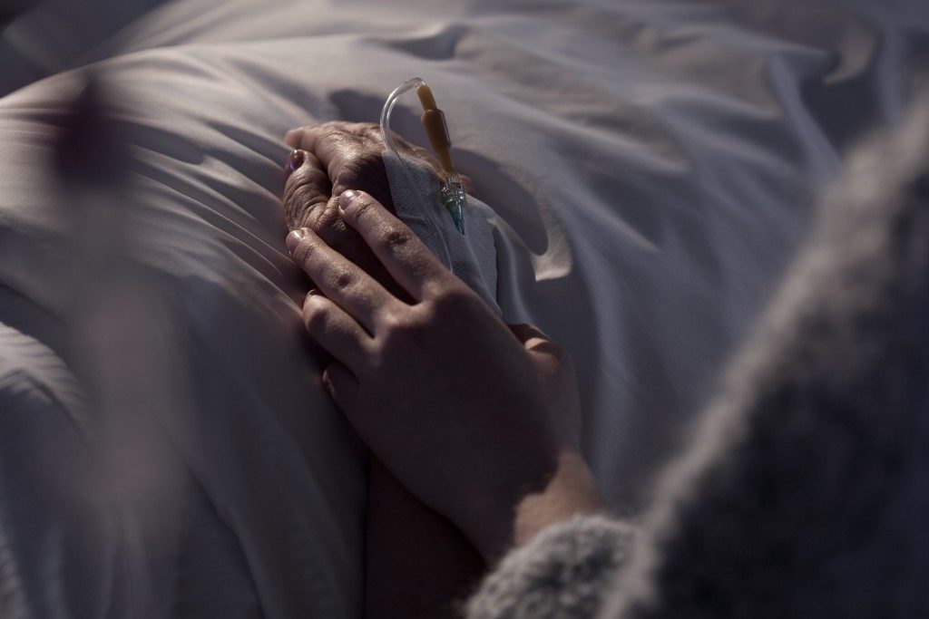 holding hand of dying woman