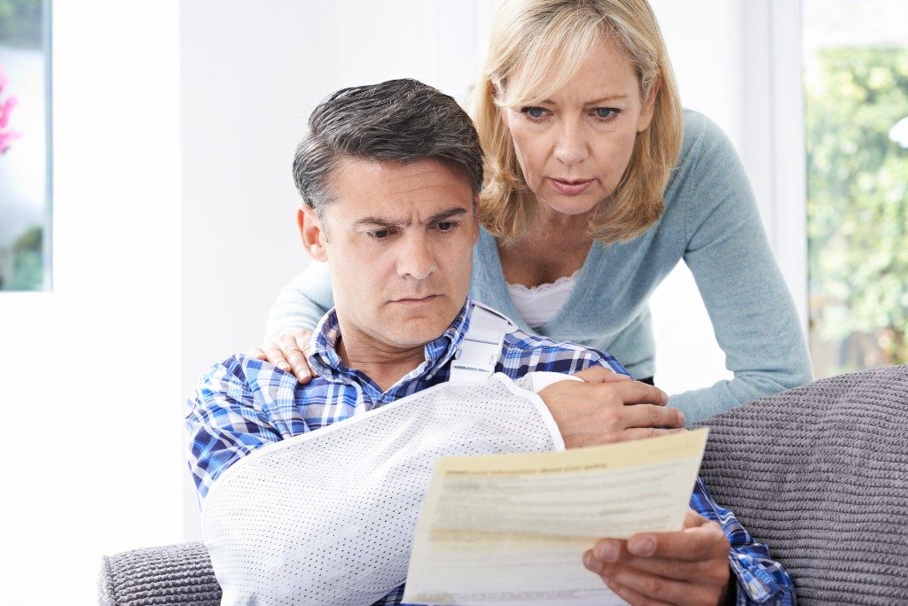 man with arm injury reading a document with his wife