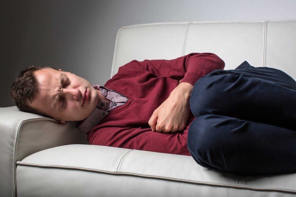 man with stomach ache lying on the couch