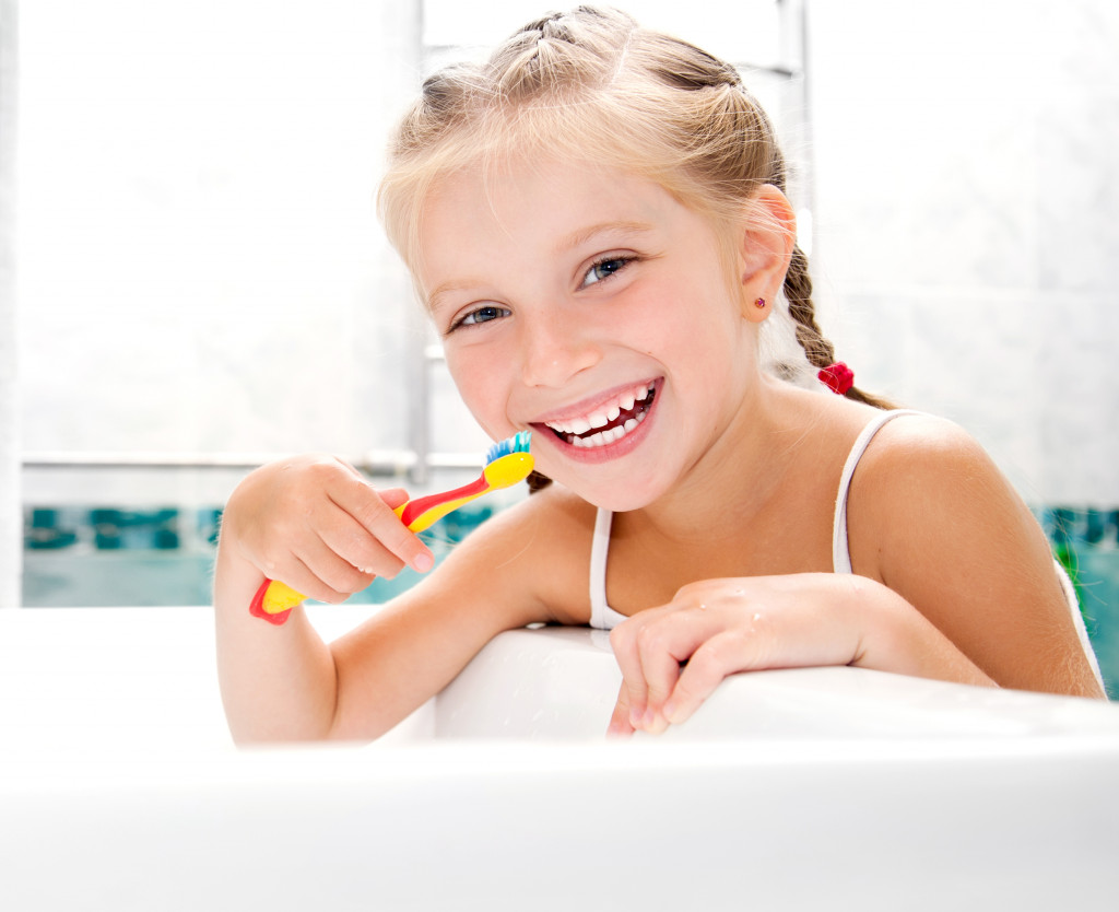 Little girl brushing teeth in bath