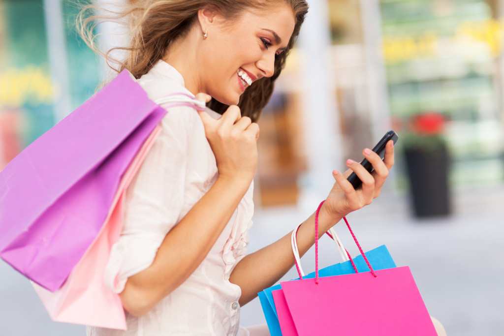 Woman texting while holding shopping bags