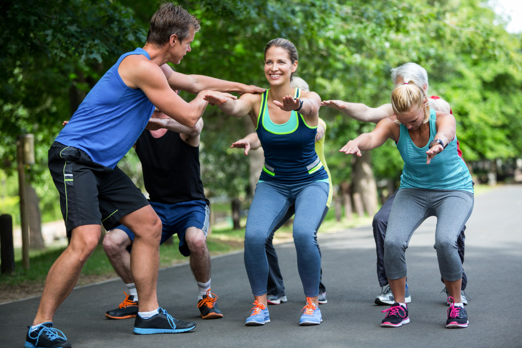 Group of people exercising at a park under the guidance of a coach.