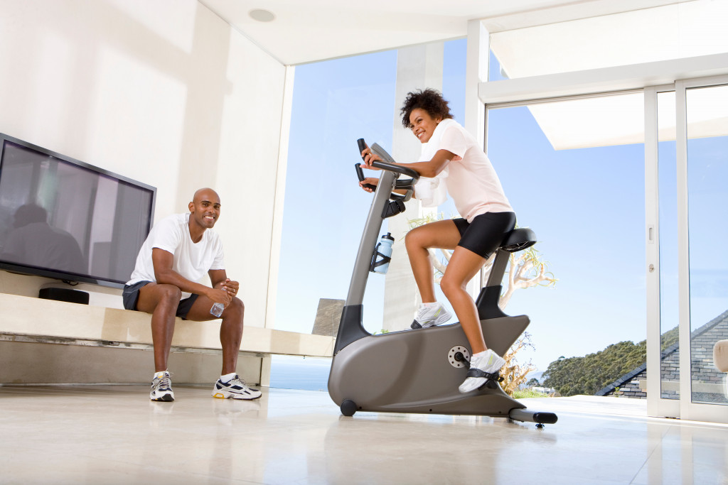 Young couple exercising at home using a stationary bike.