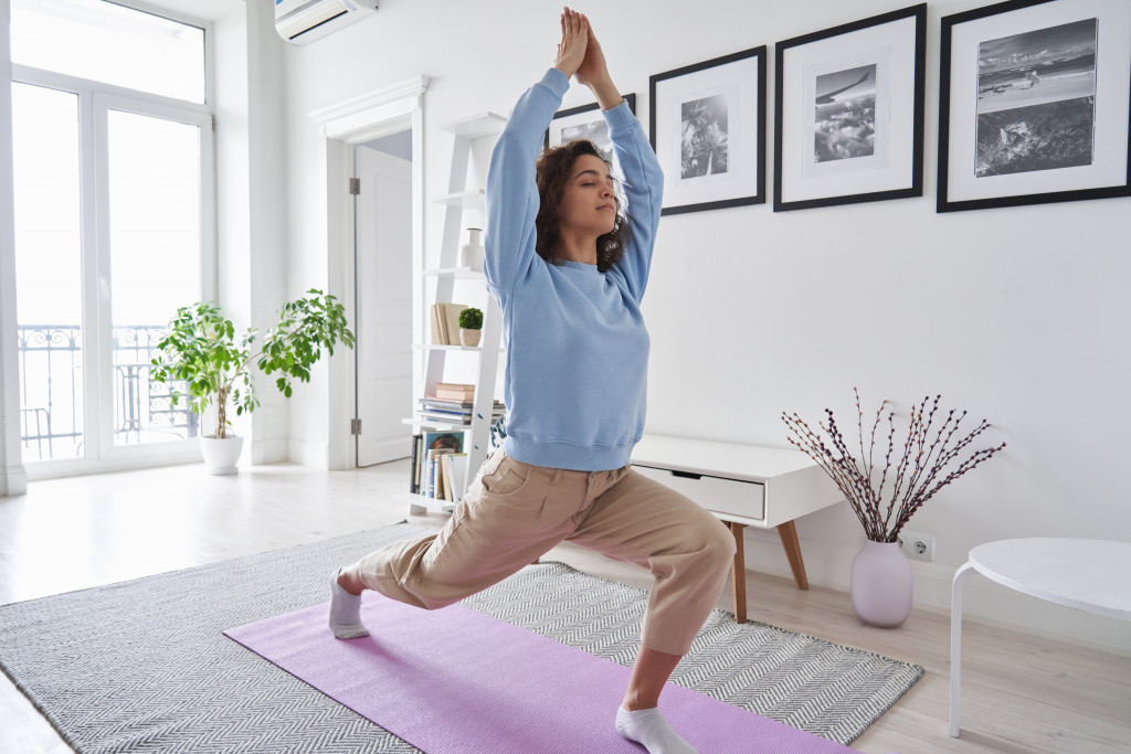 Young woman performing a yoga exercise inside the home.