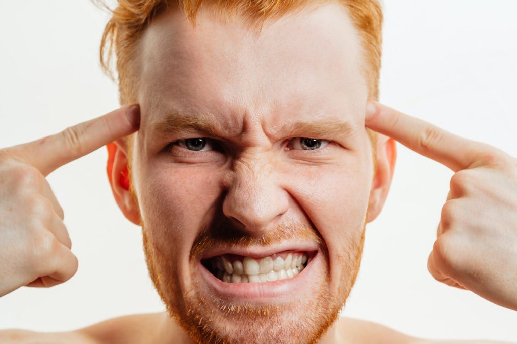 Redhead Man Clenching His Teeth and Pointing to His Temples