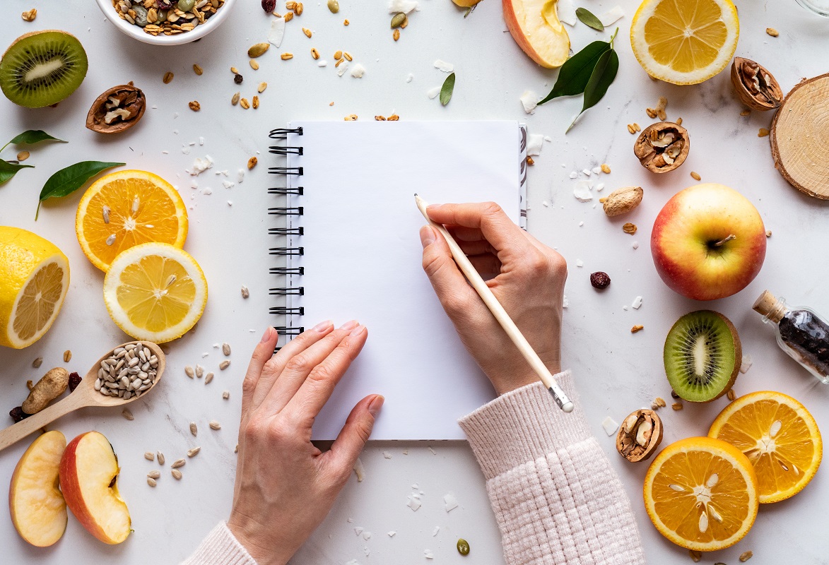 a person writes in a notebook on healthy food background